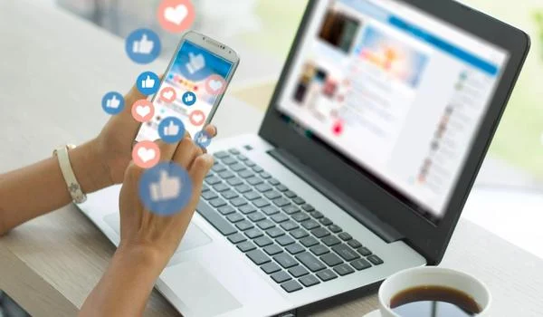 Image of laptop and a ladies hands in front with her cellphone.