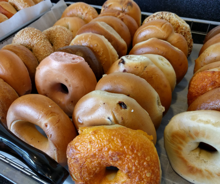 A variety of bagels in different flavors and textures arranged on a tray.